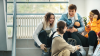 Group of high school students sitting in the hallway laughing